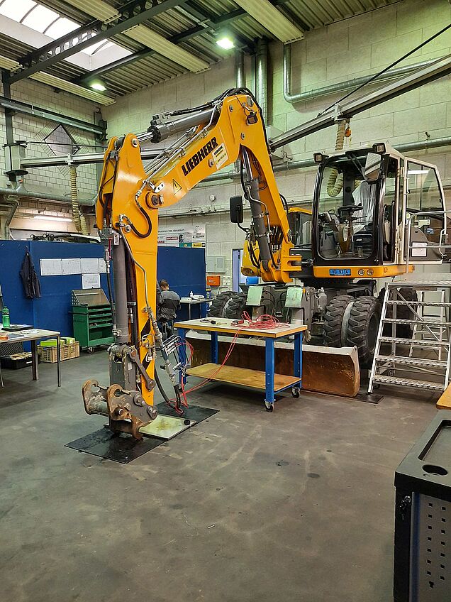 Situation d’examen dans le domaine « Effectuer des travaux spécialisés Systèmes hydrauliques » avec une pelle excavatrice de Liebherr.